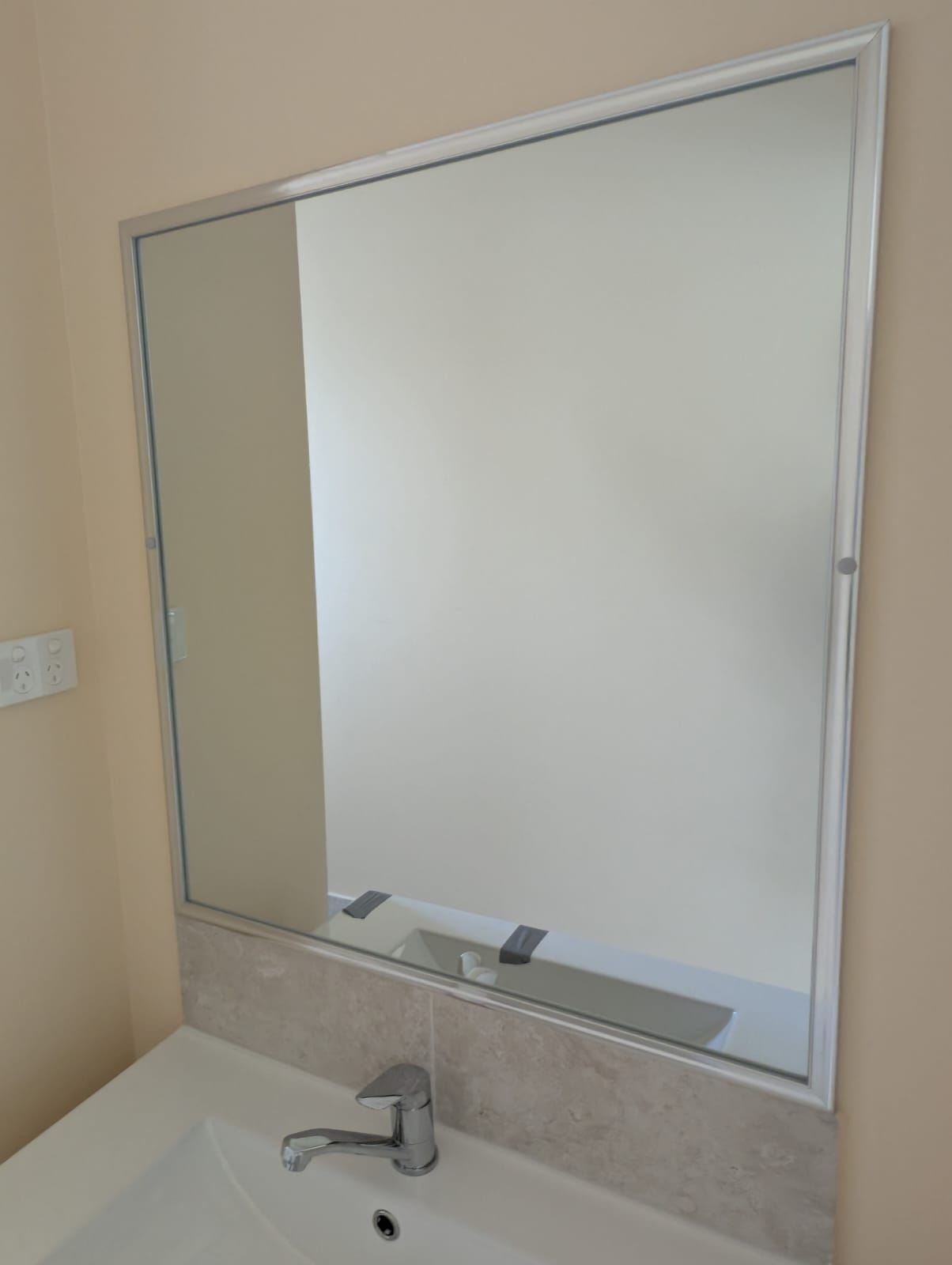 Silver framed bathroom mirror above a vanity
