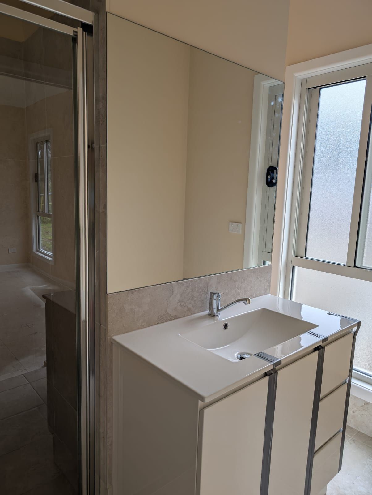 Frameless polished-edge mirror above a bathroom vanity