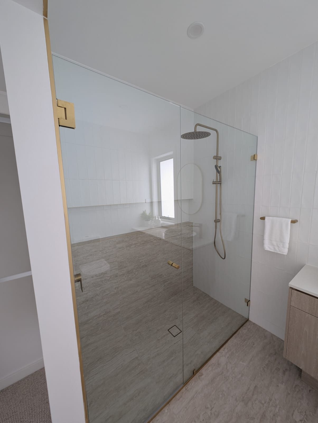 Frameless shower door and fixed panel with brushed brass hinges