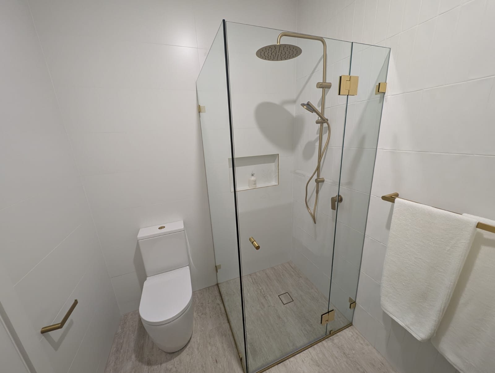 Frameless ensuite shower screen with brushed brass fittings